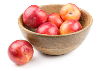 Plums red orange in a wood bowl isolated on white background.