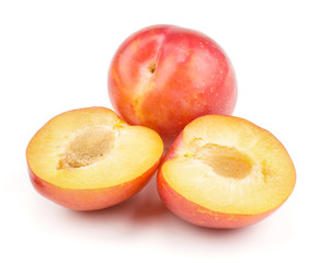 Plums red orange one whole and two section halves isolated on white background fresh and glossy.