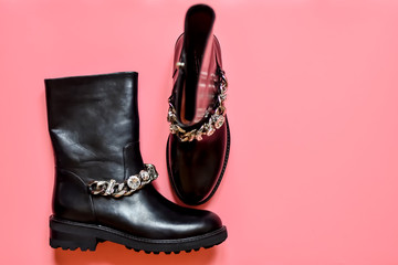 Fashionable female black boots with rhinestones-crystals and on a metal chain on a pink background. The concept of fashion. Top view. Flat lay.