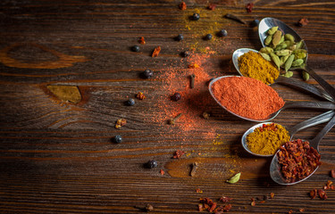 Spises in metall spoons on darck woodden table