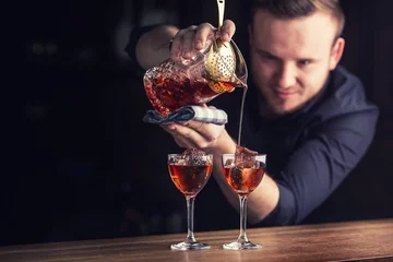 Crédence de cuisine en verre imprimé Cocktail Barman versant une boisson alcoolisée cocktail Manhattan.