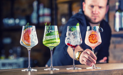 Barman in pub or restaurant preparing a gin tonic cocktail drinks in wine glasses