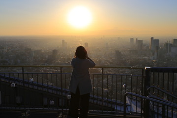 Fototapeta premium office lady watch the sunset on the top of skyscraper in tokyo