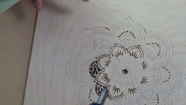 Woman making pyrography on wood, a sketch of flowers, time laps