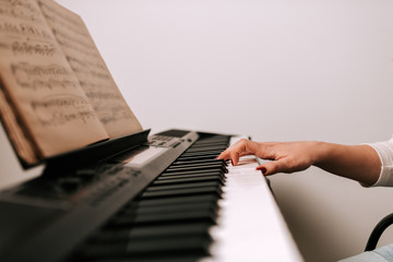 Fototapeta na wymiar Close-up image of female musician playing piano from sheet music.