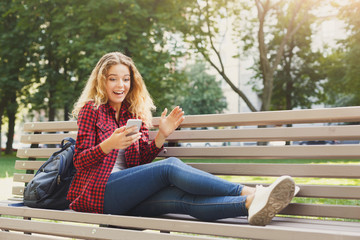 Shocked woman reading news on the smartphone outdoors