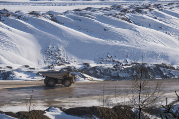 Haul truck driving through an open pit mine in winter