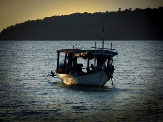 Fototapeta na wymiar Kleines altes Fischerboot in Asien läuft im Abendrot aus.