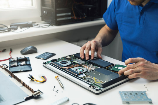 computer repairman installing new hard disk drive in laptop