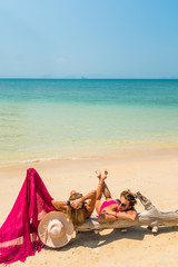Two Women sitting the beach by a tree