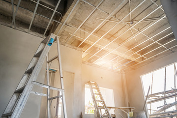 Install metal frame for plaster board ceiling at house under construction - obrazy, fototapety, plakaty