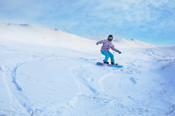 Fototapeta na wymiar One snowboarder ride from a high snowy mountain under a blue sky.