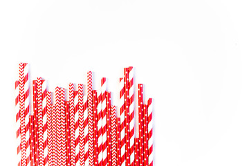 Fototapeta na wymiar A stack of red and white striped and spotted straws for cocktails on a white background. Festive mood concept. Flat lay, top view
