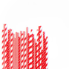 A stack of red and white striped and spotted straws for cocktails on a white background. Festive mood concept. Flat lay, top view
