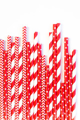 A stack of red and white striped and spotted straws for cocktails on a white background. Festive mood concept. Flat lay, top view