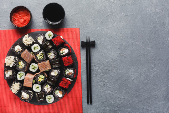 Set of black rolls with chopsticks on gray table