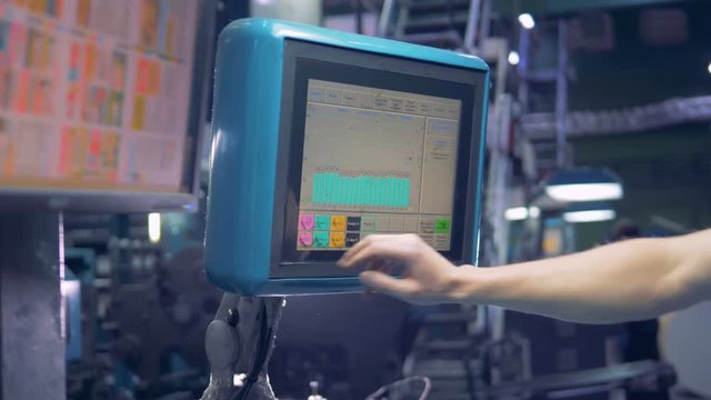 Worker sets up industrial equipment using computer touchscreen.