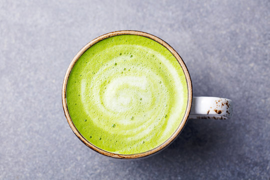 Matcha, green tea latte in a cup. Grey stone background. Top view