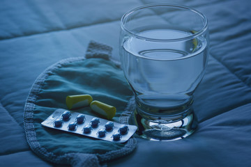 Blister pack of sleeping pills, blindfold and glass of water