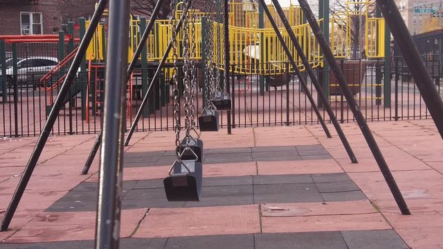Empty playground swings swaying in wind