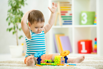 toddler boy playing indoors with developmental toy sitting on soft carpet