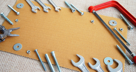 .a collage of tools, wood screws, bolts, wrenches, a small hacksaw, pasatis, nuts and washers on a wooden backing