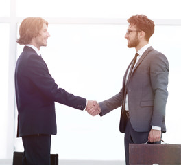 Two young businessmen greet