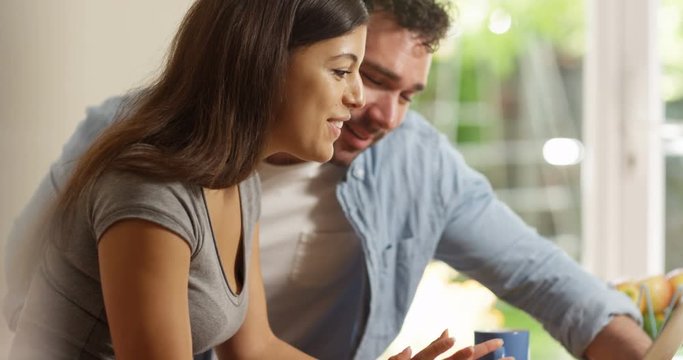 4K Happy smiling couple relaxing at home & browsing the internet together. Slow motion.