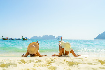 Two 2 young beautiful girls sunbathing on the tropical beach