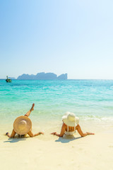 Fototapeta na wymiar Two 2 young beautiful girls sunbathing on the tropical beach