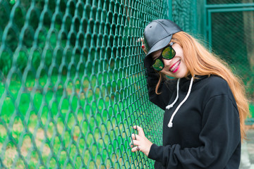 Cool Hipsters girl in black hood with black hat and black sunglass,lifestyle of teenage,thailand people,young woman posing on fence