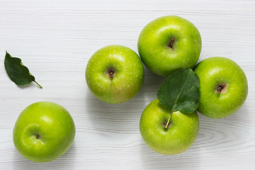 Green apples with leaves on white wooden table Top view