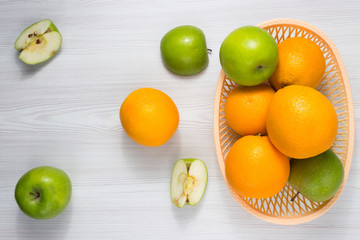 Green apples and oranges on wooden table. Fruits