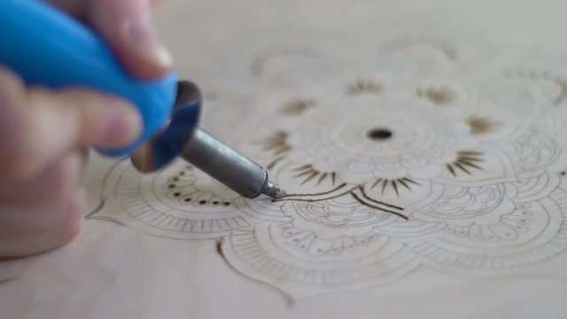 Burning on a tree with a pyrograph of a flower