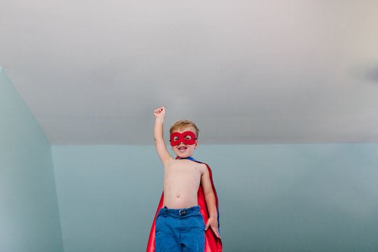 Cute young boy playing superhero at home