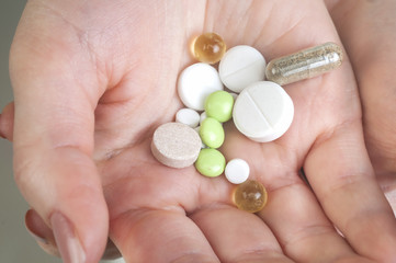 Multicolor pills in your palm, medications in woman's hand