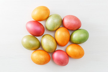 Happy Easter concept. Multicolored Easter eggs on white wooden table. Top view.