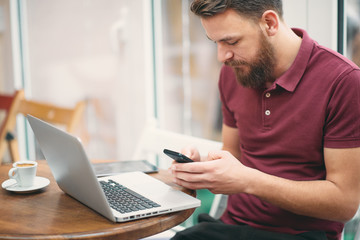 Young man sitting in cafe and using smart phone.