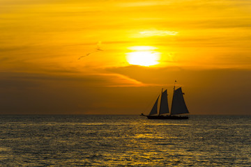 USA, Florida, Impressive orange sunset sky behind two master sailing boat and reflections on water