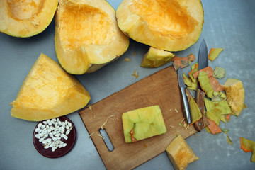 Cubes of a carved ripe pumpkin with a cutting board and a knife on the table. The concept of vegetarian food. View from above.
