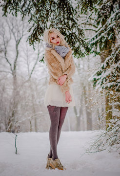 A charming girl standing by the trees in a snowy forest