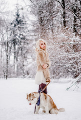 A magic girl stands with her dog in the winter forest