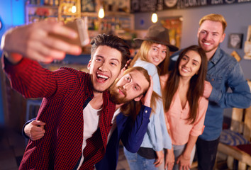 Selfie Time. Young Group of Friends Partying In A Nightclub And Toasting Drinks. Happy Young People With Cocktails At Pub. The People Have A Great Mood And They Smile A Lot.