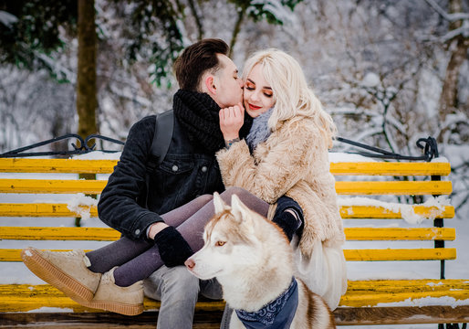 Sweet couple hug each other on a bench with her dog