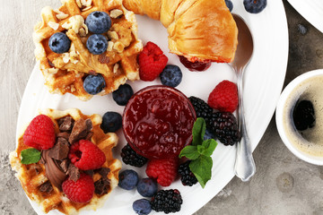 Delicious breakfast with fresh croissants and ripe berries and jam