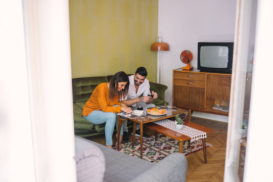 Fototapeta Friends Reading Magazine over Breakfast in Living Room