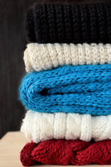 Knitted scarves of different colours are piled carefully