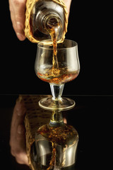 Fototapeta na wymiar Cognac is poured from a bottle into glass