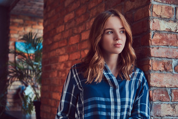 Naklejka premium Close-up portrait of a young sensual girl leaning against a bric