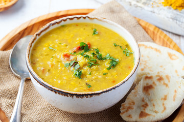 Lentil soup with pita bread in a ceramic white bowl on a wooden background. Close up.